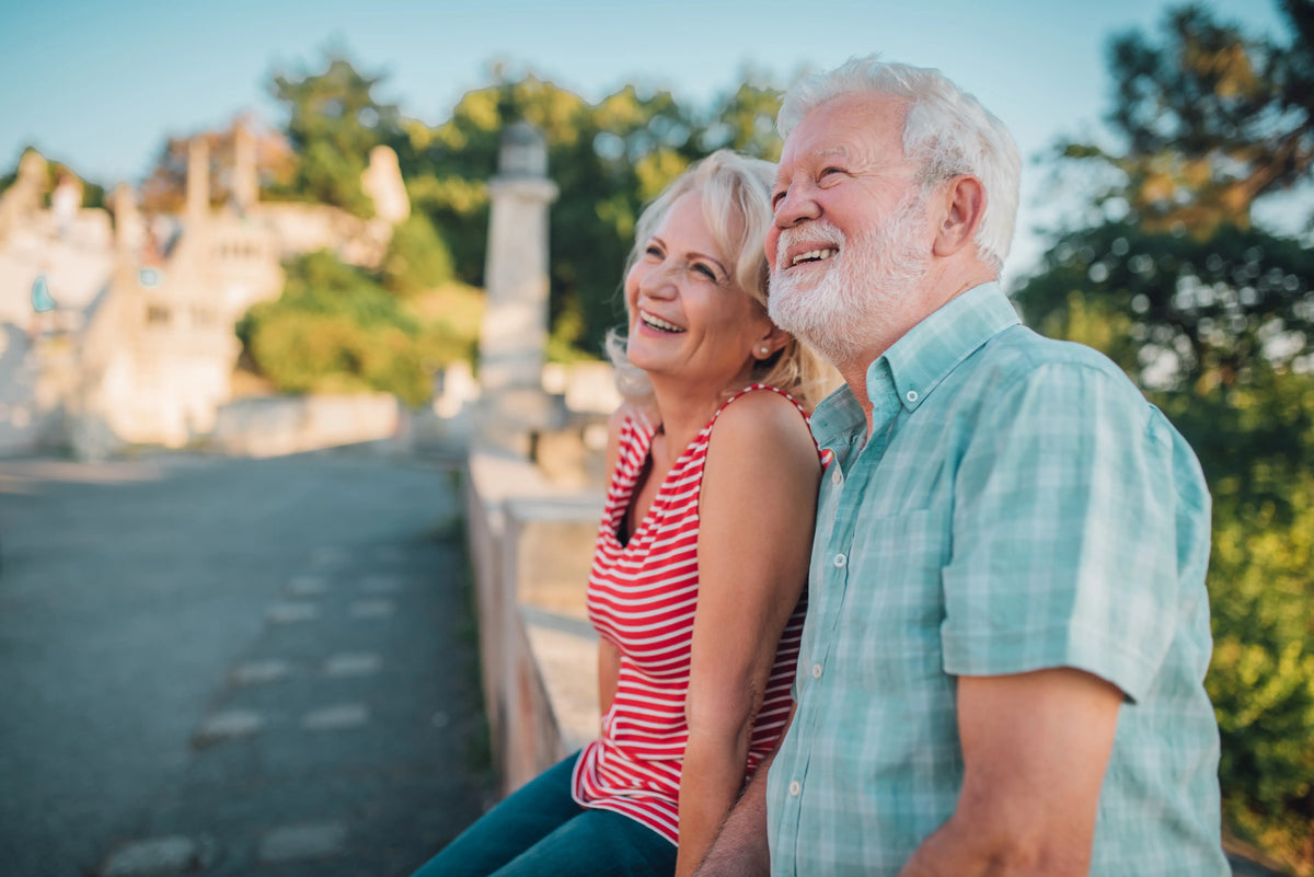 The elderly couple leaned against the stone railing, gazing into the distance, and smiled.