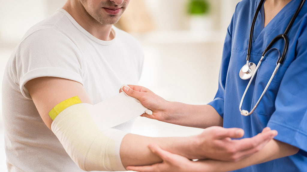 A nurse helps the patient change the xeroform dressing.