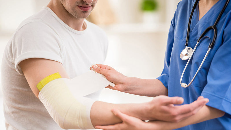 A nurse helps the patient change the xeroform dressing.